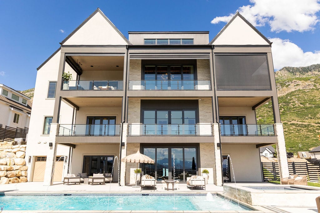 Three-story rear elevation with water features and mountain views of the Room with a View custom home featured in the 2025 Utah Valley Parade of Homes by E Builders