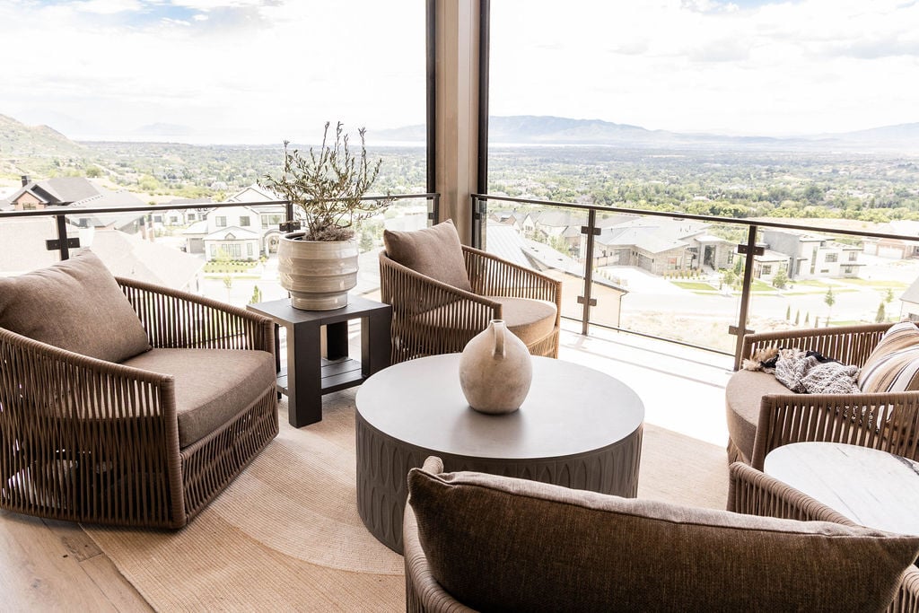 Upper balcony with woven lounge seating and panoramic mountain views in the Room with a View custom home featured in the 2025 Utah Valley Parade of Homes by E Builders
