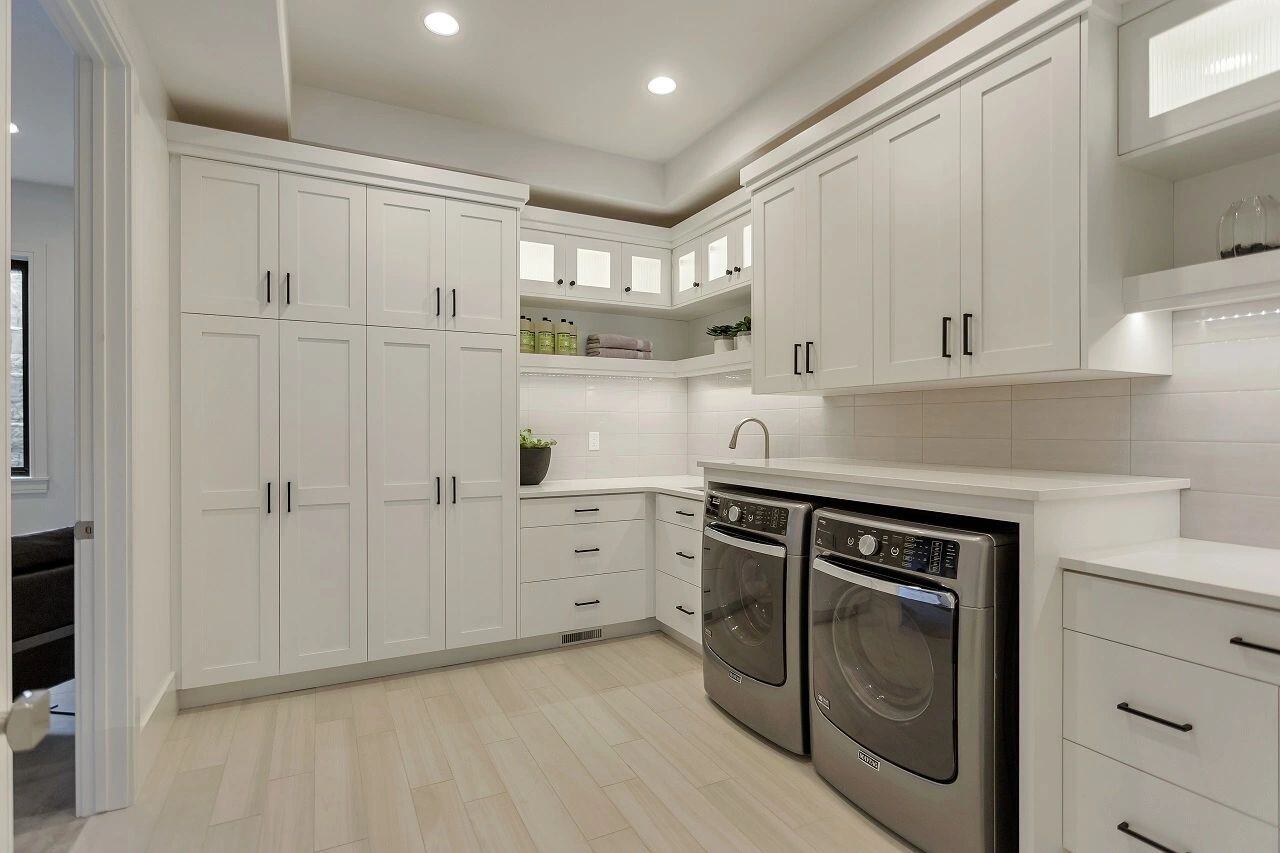 Custom laundry room featuring white cabinetry and counter space in a custom home in Salt Lake City, UT built by E Builders