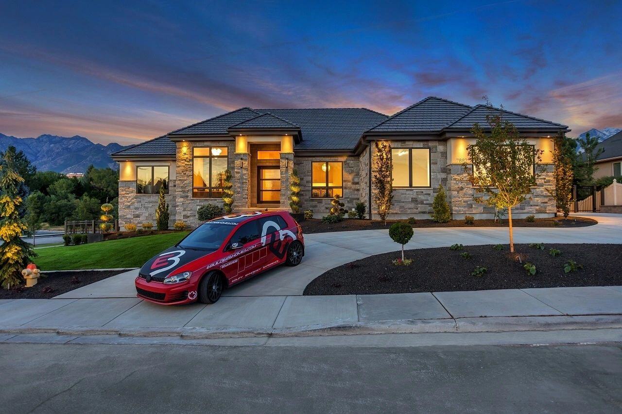 Front exterior with stone facade and branded E Builders car at custom home in Salt Lake City, UT