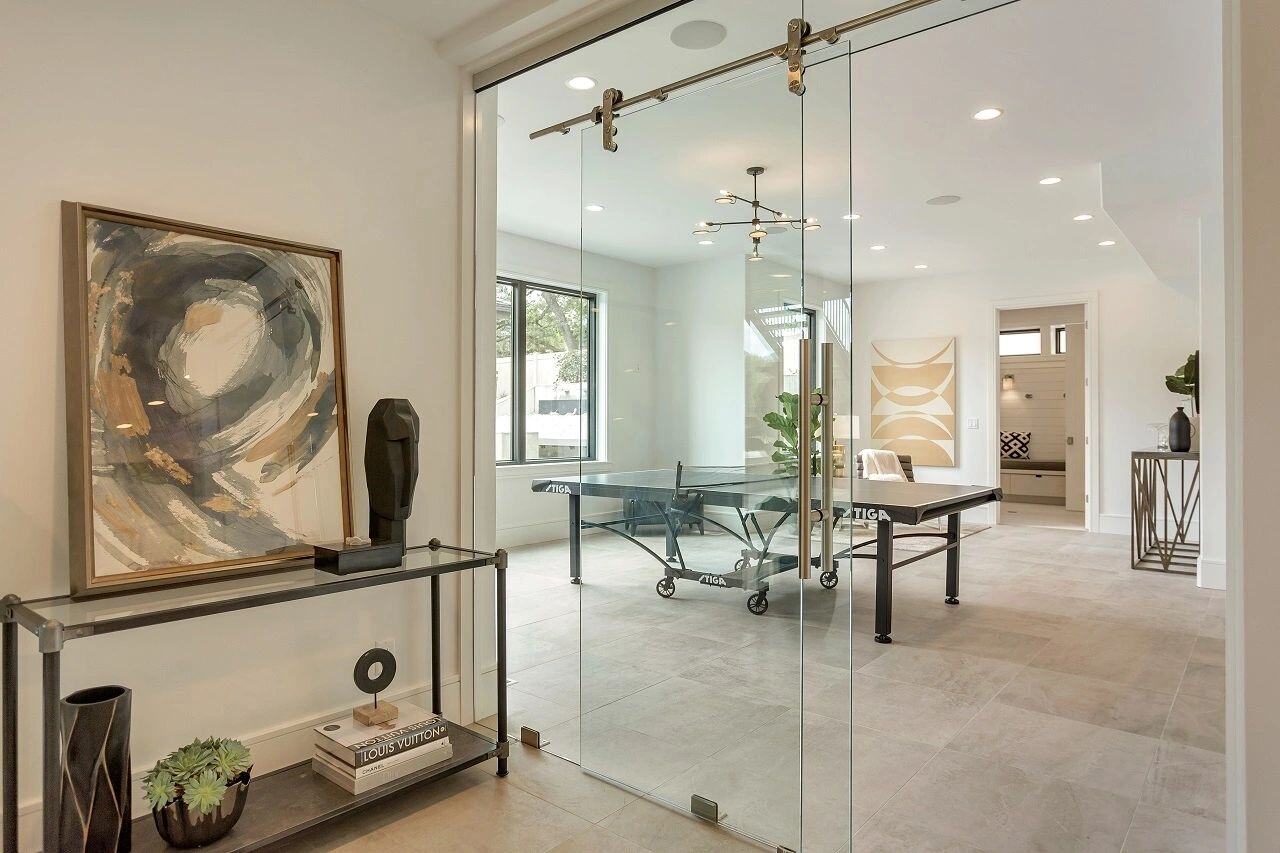 Glass-enclosed game room with ping pong table in a custom home in Salt Lake City, UT built by E Builders
