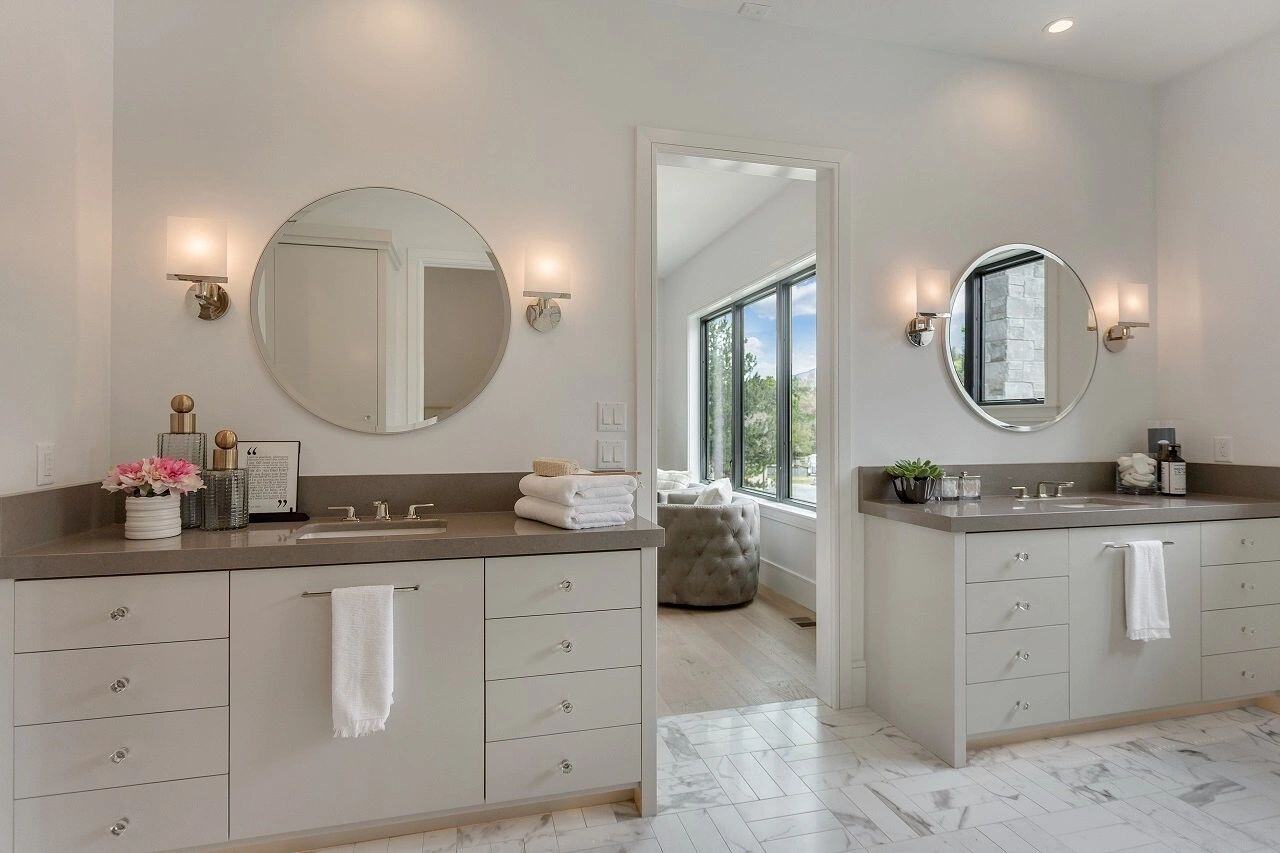 Modern master bath featuring dual sinks and round mirrors in a custom home in Salt Lake City, UT built by E Builders