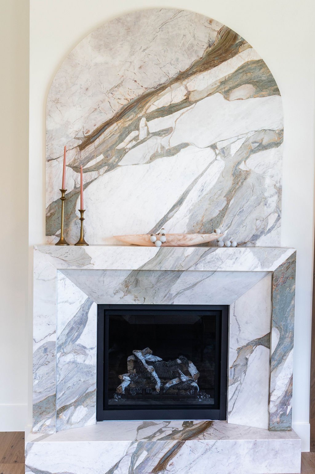Arched marble fireplace in the master bedroom featuring Calcutta Michaelangelo stone in a custom home featured in the 2025 Utah Valley Parade of Homes