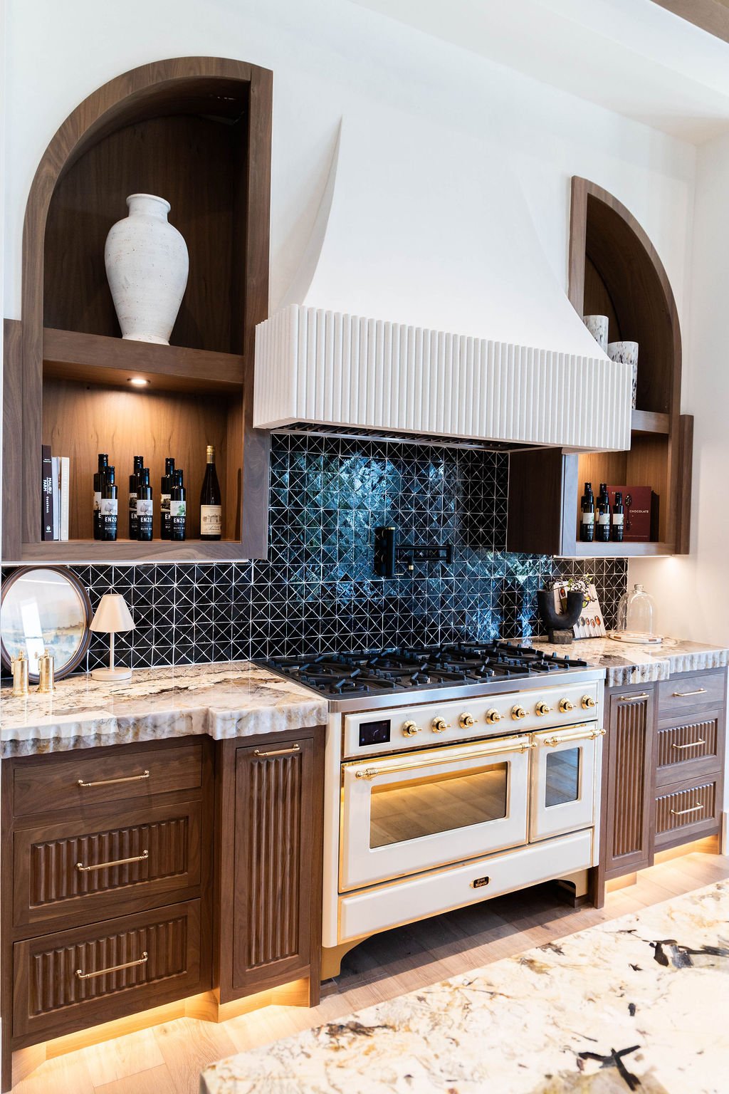 Arched walnut cabinetry with detailed backsplash and professional range in a custom home featured in the 2025 Utah Valley Parade of Homes