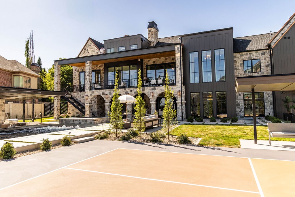 Backyard view of custom home with stone arches, modern landscaping, and patio, featured in the 2025 Utah Valley Parade of Homes