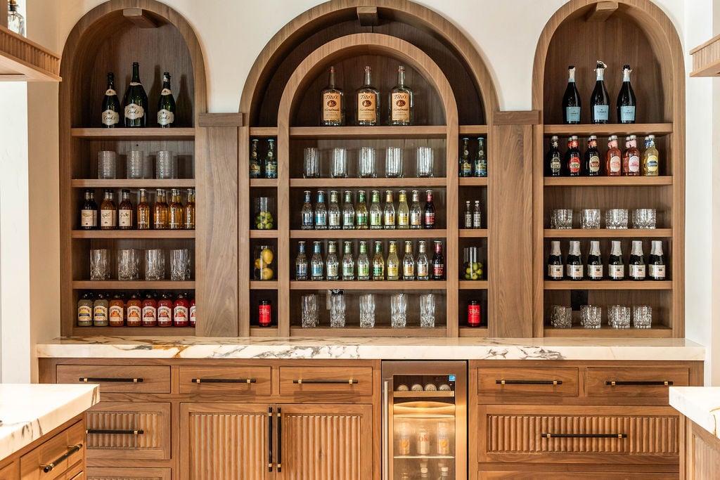 Custom back bar with Walnut arches and glass shelving in a custom home featured in the 2025 Utah Valley Parade of Homes