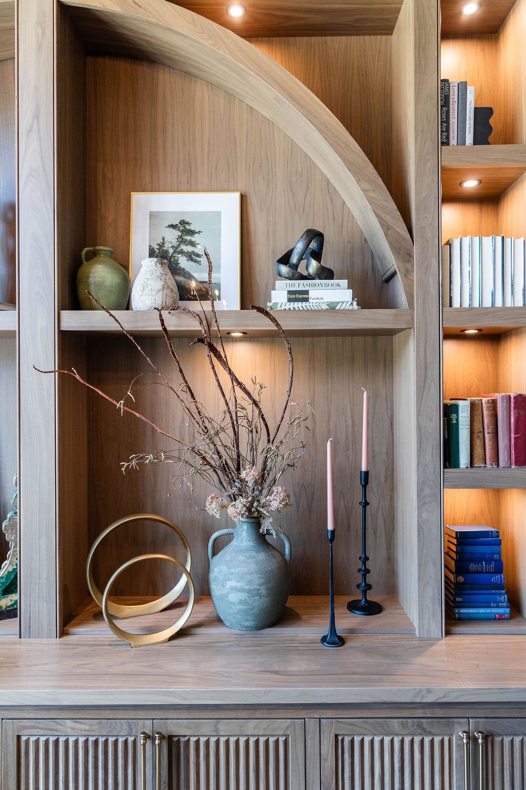 Custom wood shelving with arched detail and curated decor in a Utah Valley Parade of Homes office
