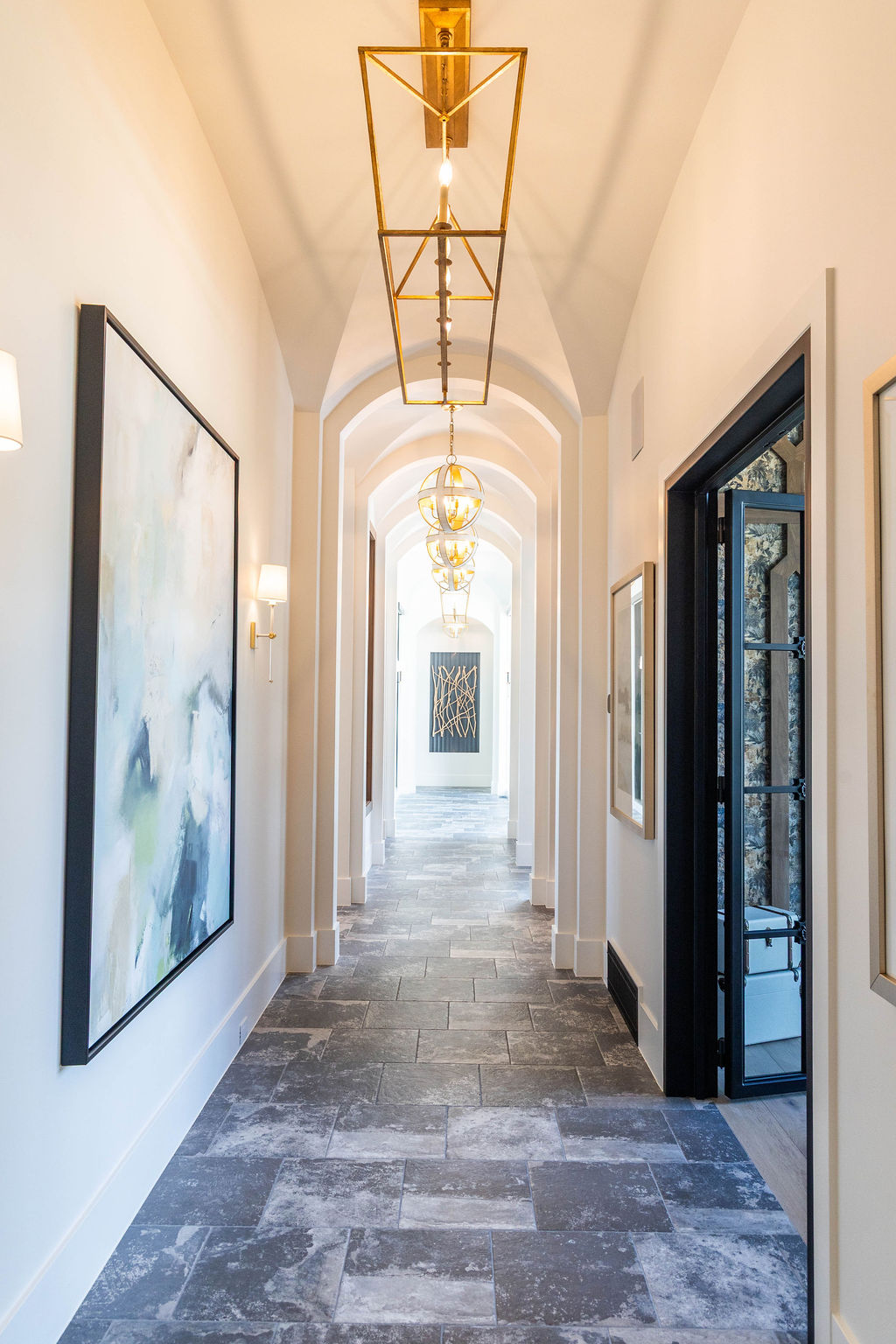 Elegant arched hallway with statement lighting and abstract wall art in a custom home featured in the 2025 Utah Valley Parade of Homes
