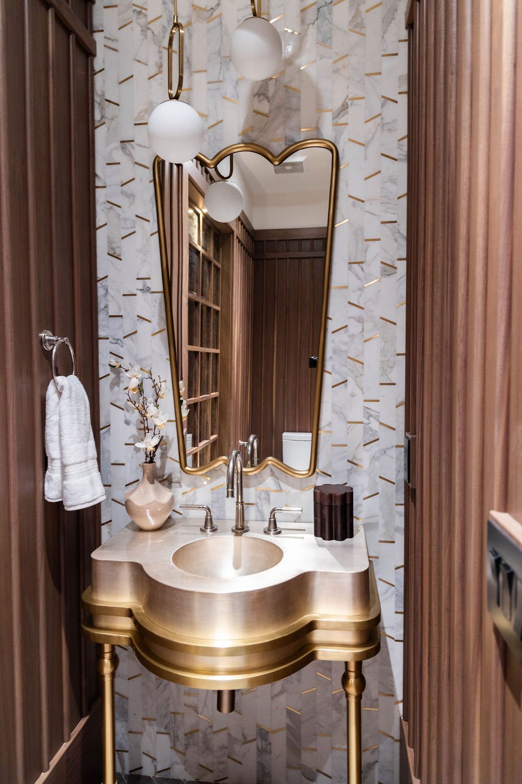 Elegant powder bathroom with scalloped gold vanity and marble wall in a custom home featured in the 2025 Utah Valley Parade of Homes