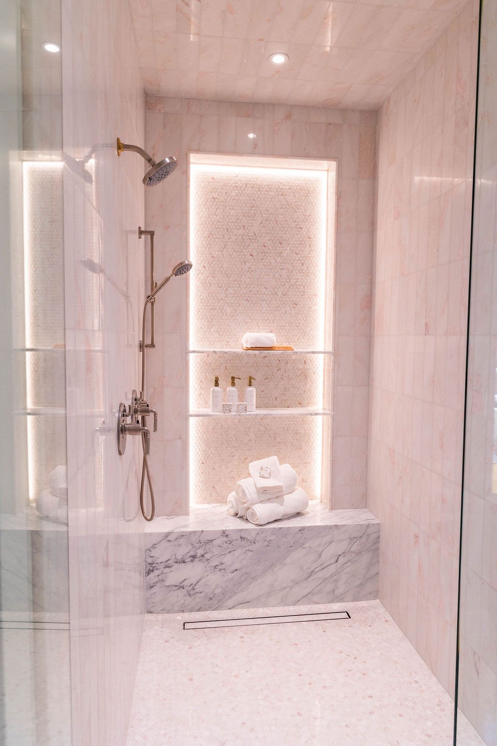 Elegant walk-in shower with soft pink tile and recessed lighting in a custom home featured in the 2025 Utah Valley Parade of Homes