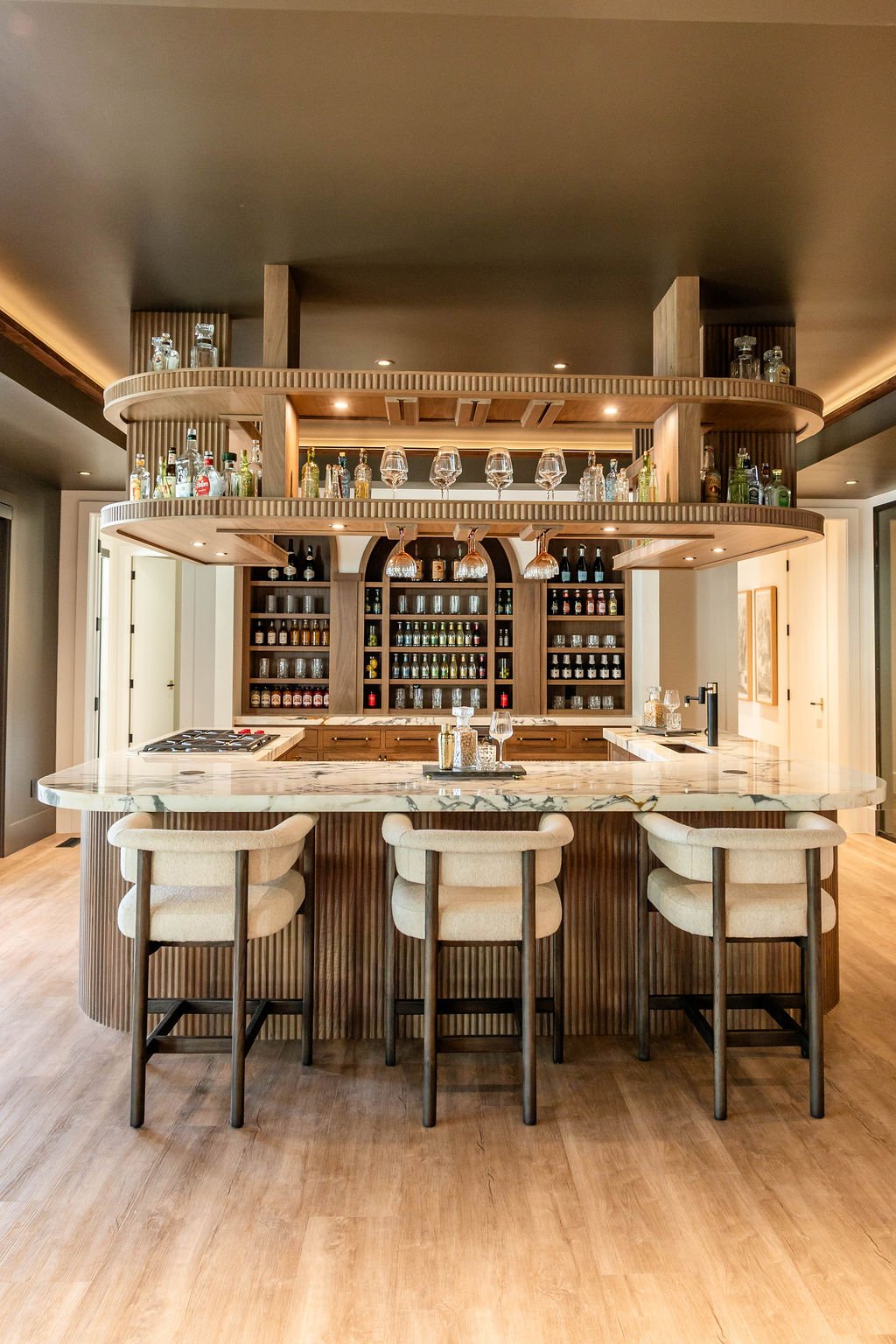Luxurious wet bar with arched wood cabinetry and marble surface in a custom home featured in the 2025 Utah Valley Parade of Homes