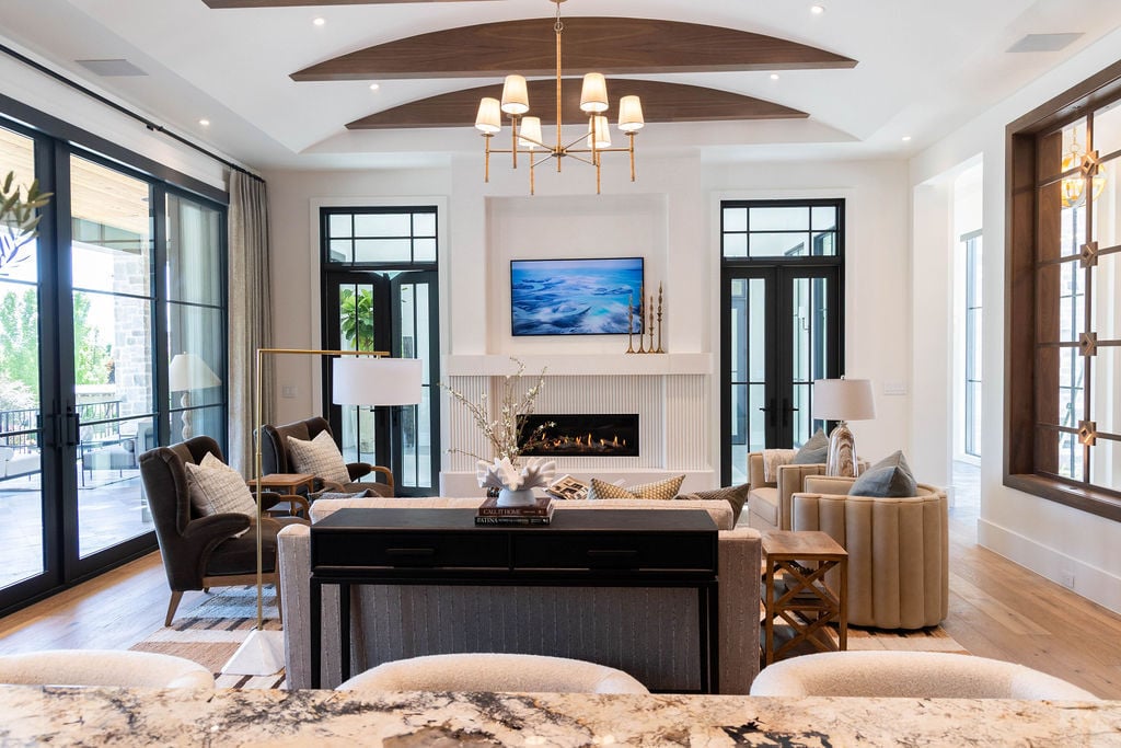 Open great room with architectural ceiling beams and modern fireplace in a custom home featured in the 2025 Utah Valley Parade of Homes