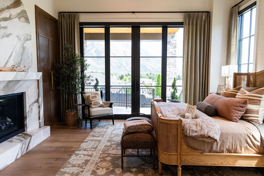 Primary bedroom with Calcutta marble fireplace and mountain views in a custom home featured in the 2025 Utah Valley Parade of Homes
