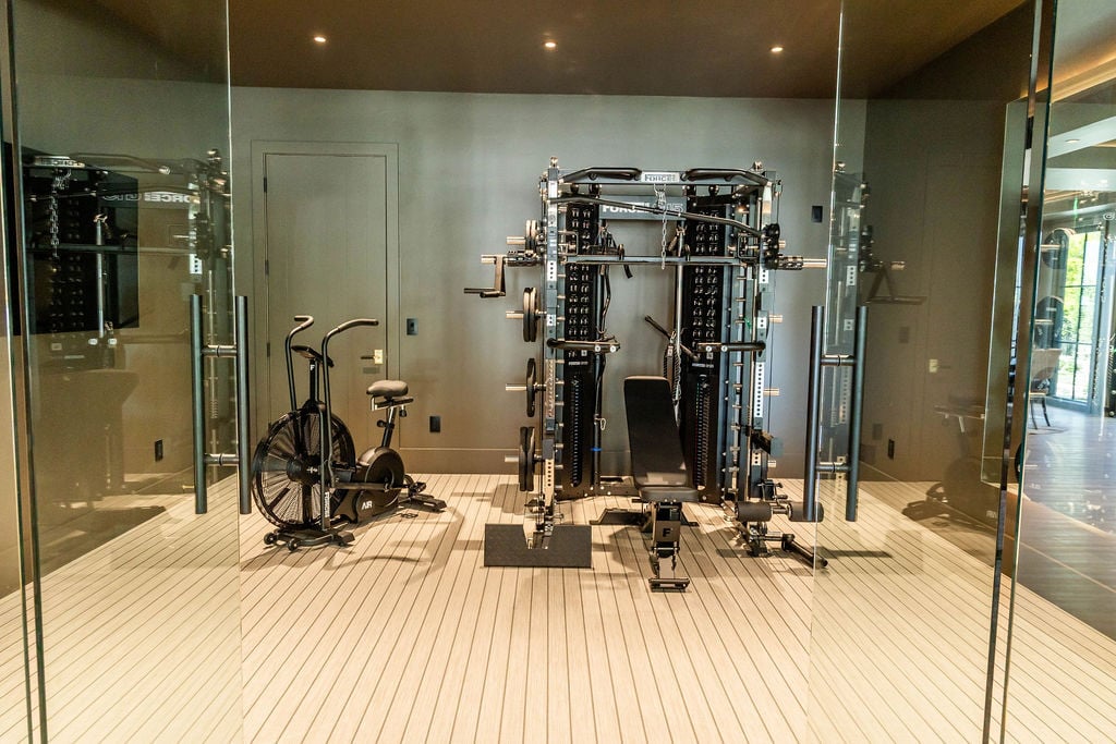 Sleek glass-enclosed gym with matte black walls and professional gear in a custom home featured in the 2025 Utah Valley Parade of Homes