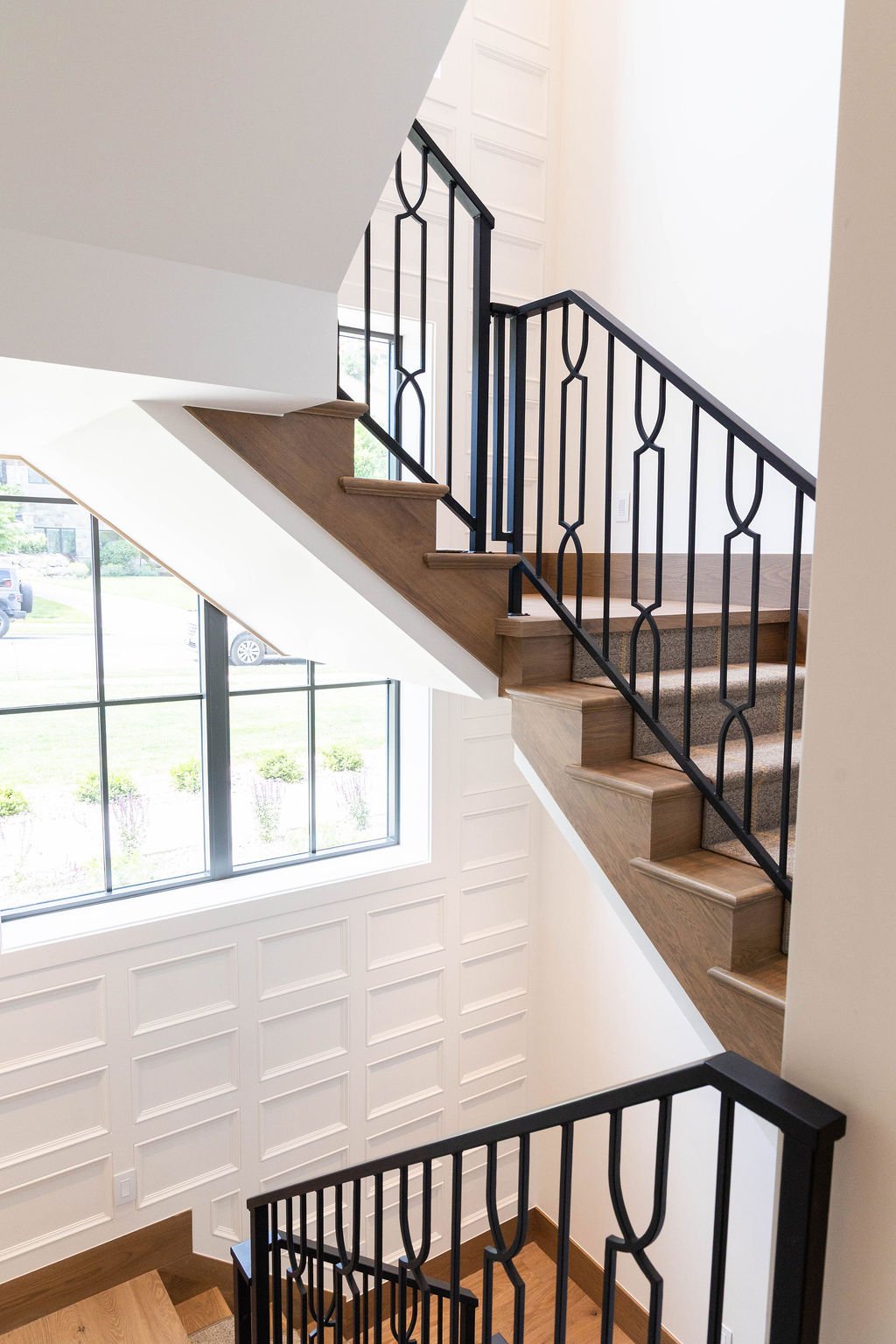 Staircase with Stitchery Stipe runner and black iron railing in a custom home featured in the 2025 Utah Valley Parade of Homes