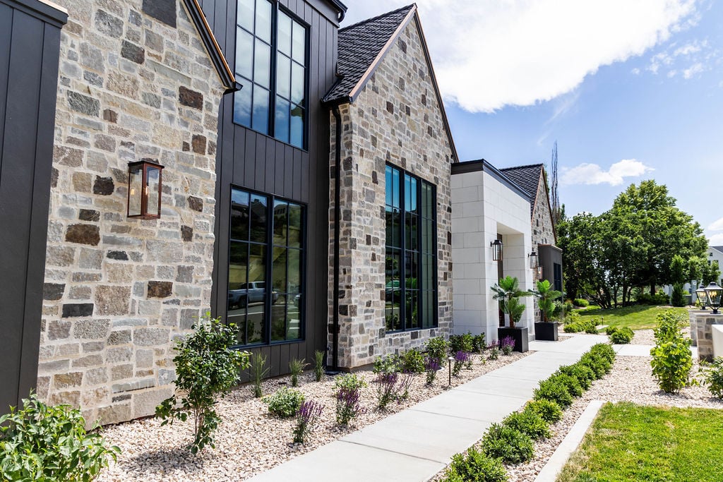 Stone and metal exterior of a custom home featured in the 2025 Utah Valley Parade of Homes with manicured landscaping