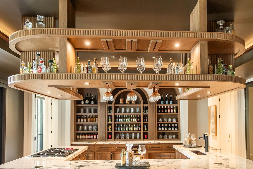 Suspended Walnut bar shelves and hanging glass rack in a custom home featured in the 2025 Utah Valley Parade of Homes