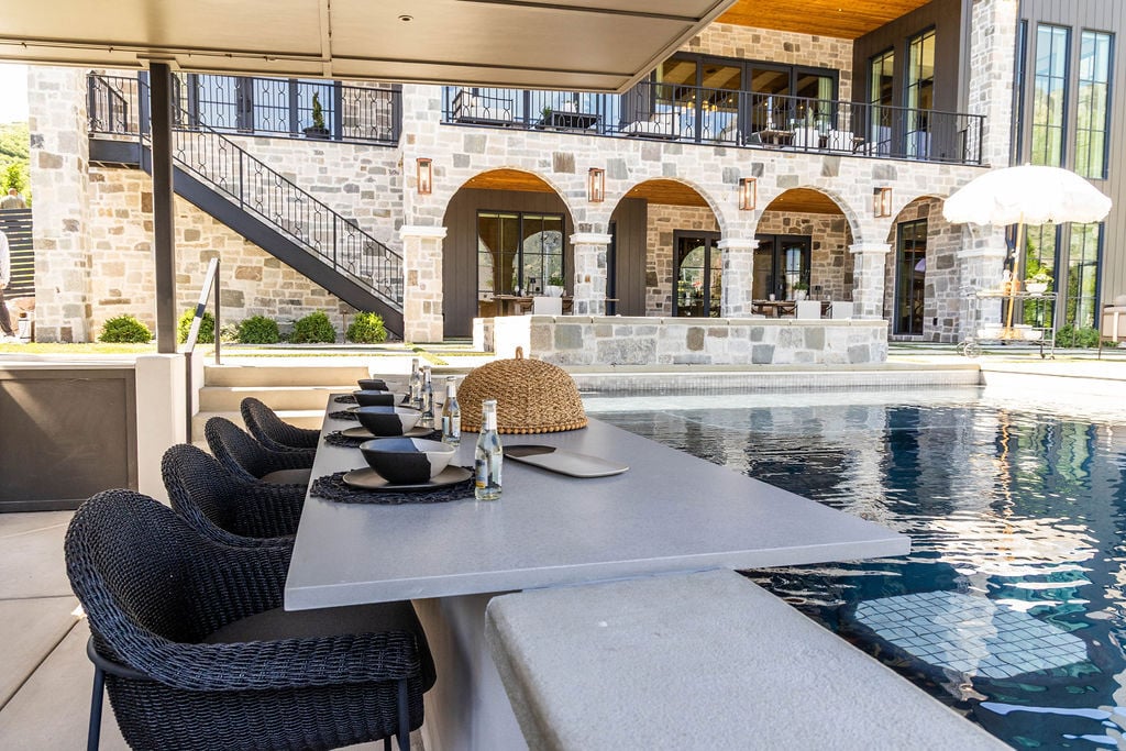 Swim-up bar with shaded seating and stone backdrop in a custom home featured in the 2025 Utah Valley Parade of Homes