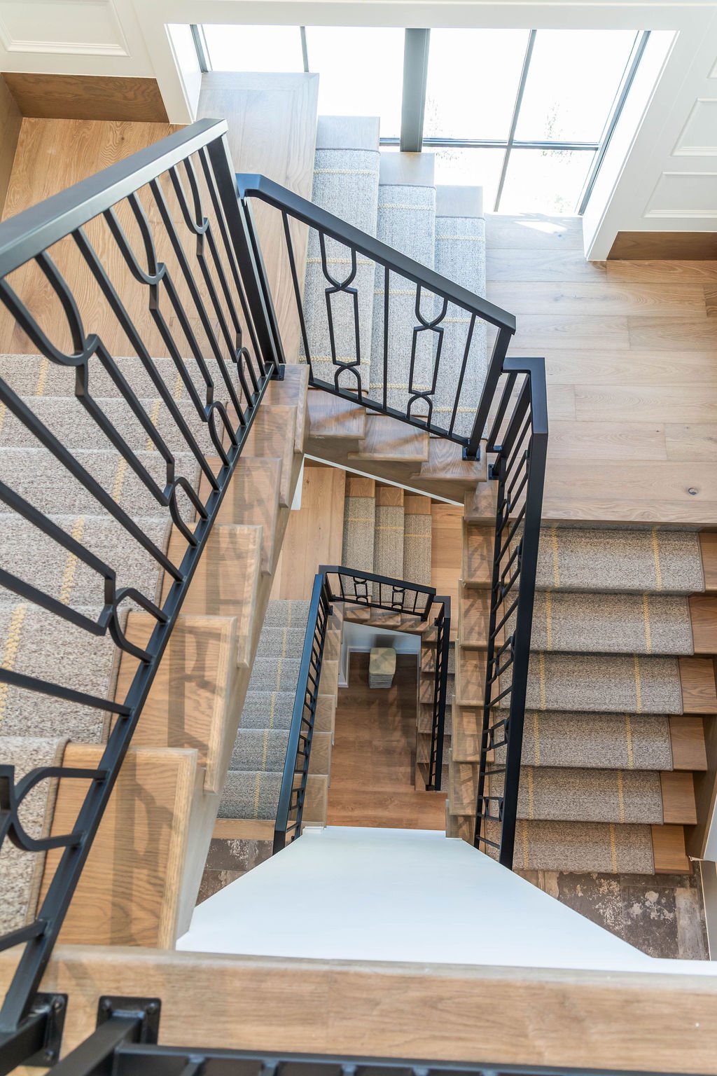 Top-down view of wood stairs with Stitchery Stipe runner in a custom home featured in the 2025 Utah Valley Parade of Homes