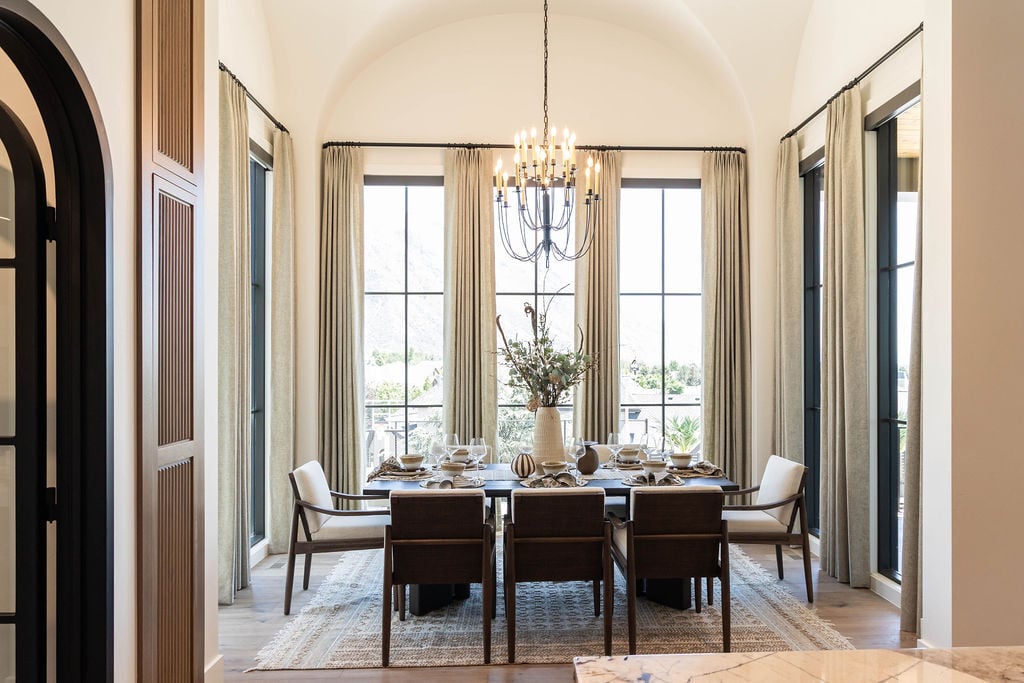 Vaulted dining room with tall windows and classic decor in a Utah Valley Parade home