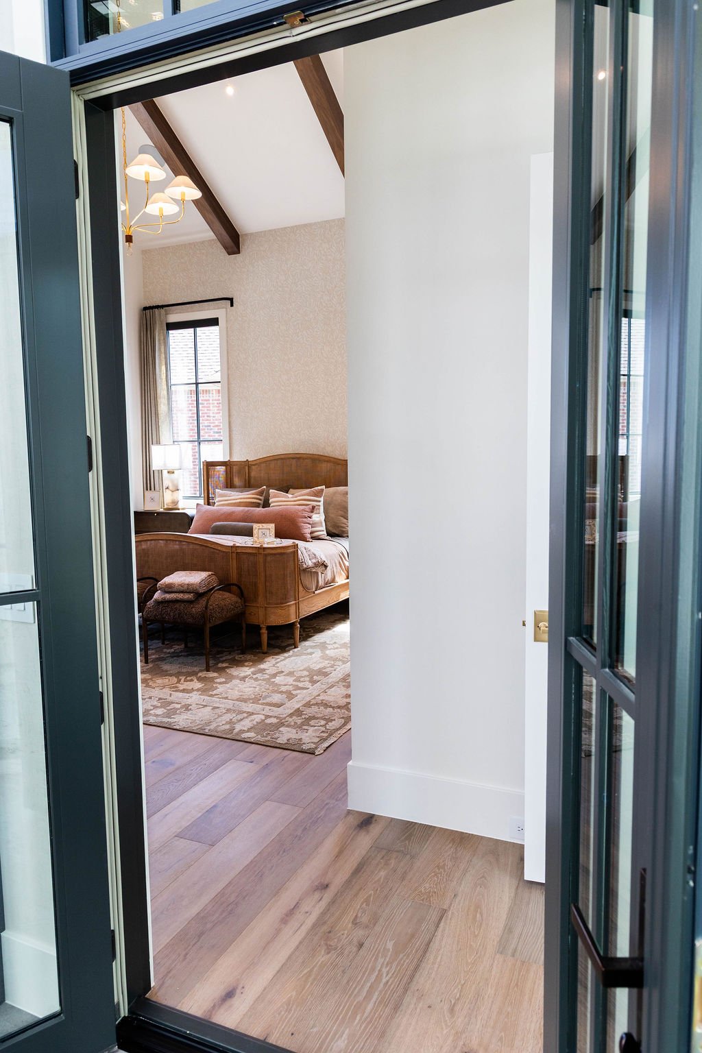 View into the primary bedroom featuring vaulted ceiling and wood beams in a custom home featured in the 2025 Utah Valley Parade of Homes