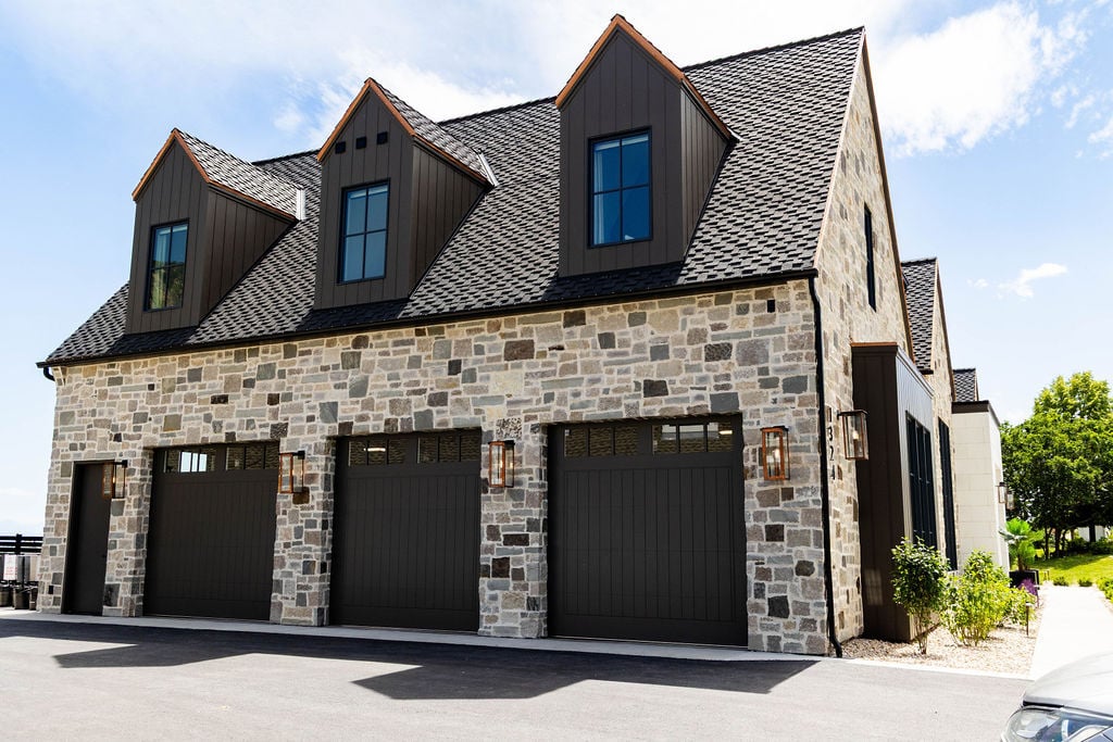 Three-car garage façade with stone and board-and-batten accents in a custom home featured in the 2025 Utah Valley Parade of Homes