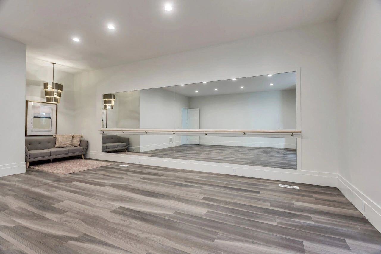 Basement dance room with wood flooring and ballet barre in a custom home in Utah built by E Builders